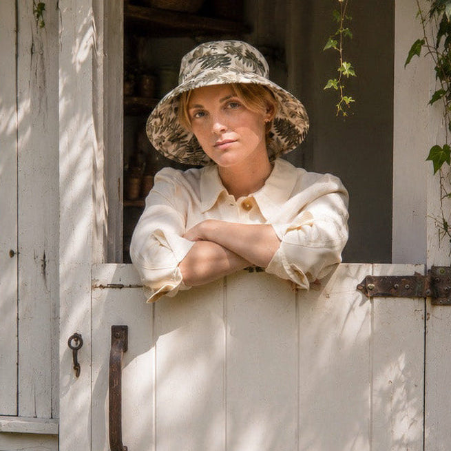 Woman in Fern Print Sun Hat Leaning out of Garden Shed