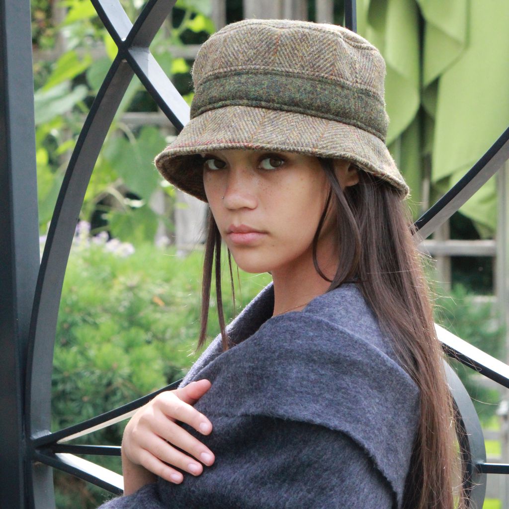 woman in harris tweed bucket hat standing in front of gate at vineyard