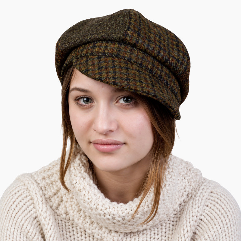 woman wearing ivory knit sweater and harris tweed pageboy hat in olive and copper plaid