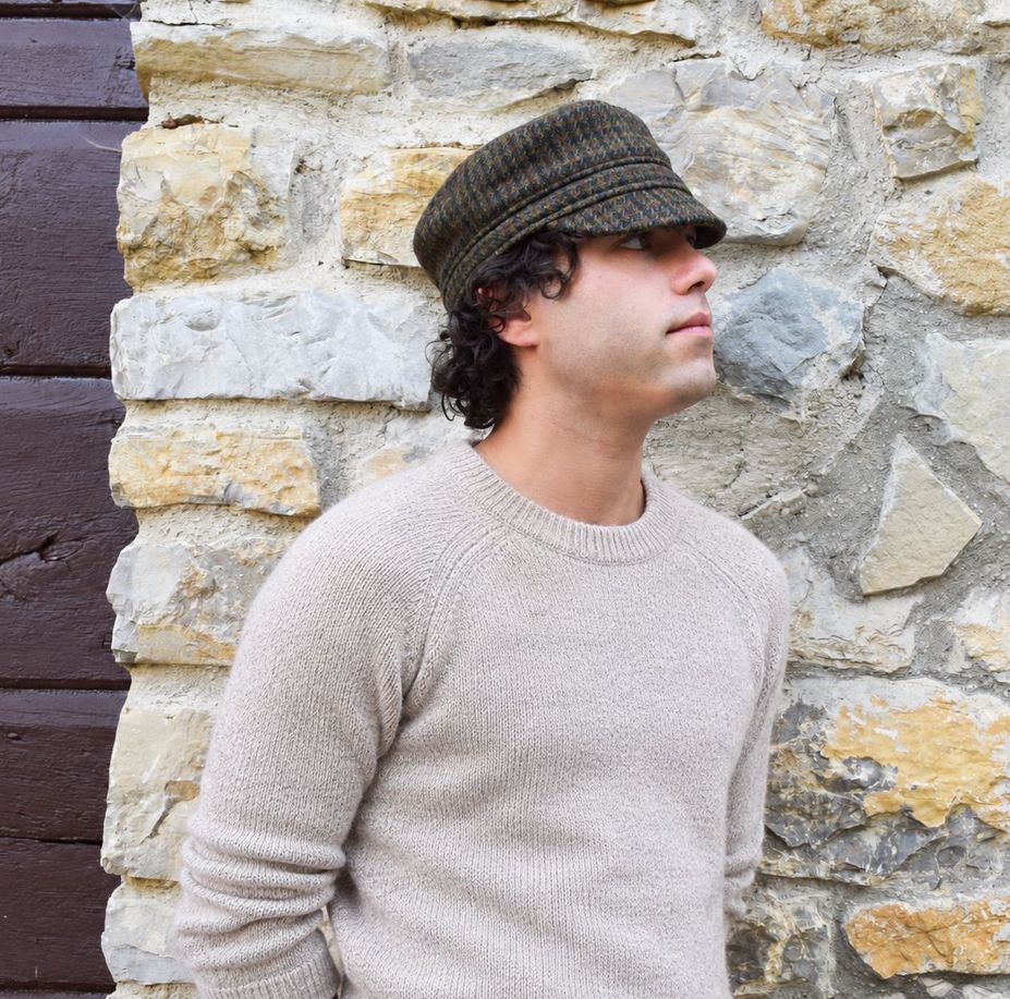 Man wearing harris tweed cap leaning on stone garden wall